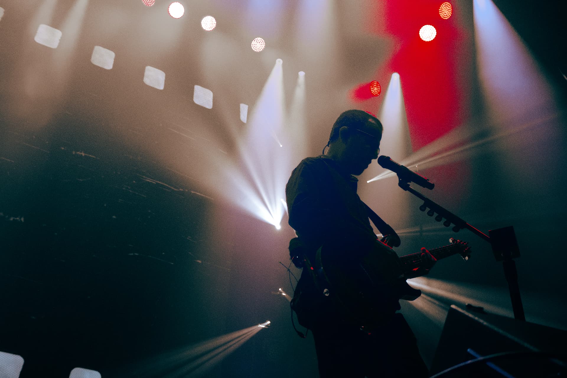 Guitarist silhouetted against beams of white and red stage light